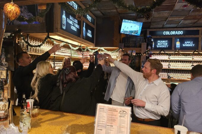 Group toasting at the bar inside Full Throttle Distillery event space with whiskey and festive decor.