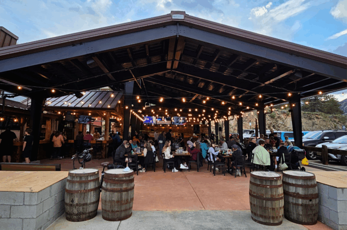A busy outdoor patio with string lights and people dining at Full Throttle Distillery, a must-visit spot on any Estes Park Day Trip.