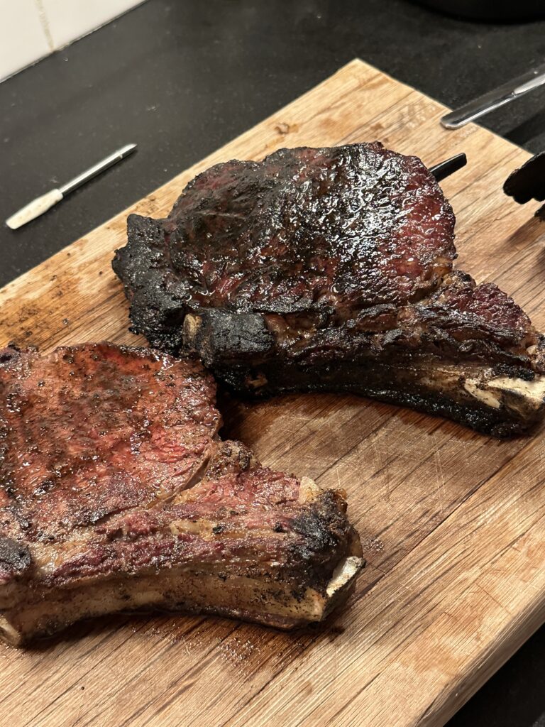 Two large smoked meat cuts on a wooden board, with a rich crust from the BBQ seasonings for a smoked flavor.