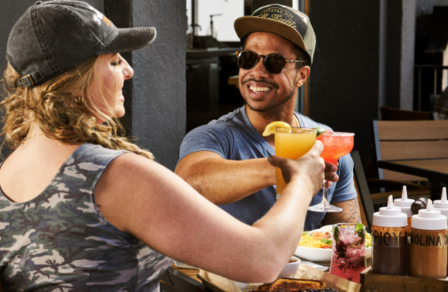 Two people toasting with drinks, celebrating a perfect Date at Full Throttle Distillery.