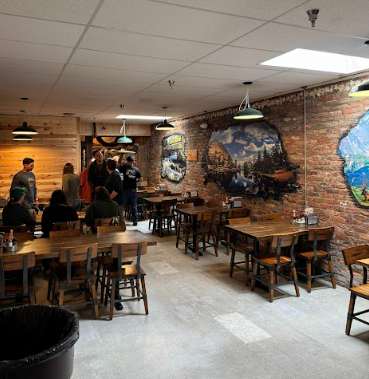 Rustic indoor dining area with wooden tables, brick walls, and mountain murals, perfect for a cozy Plan Your Wedding at Estes Park event.