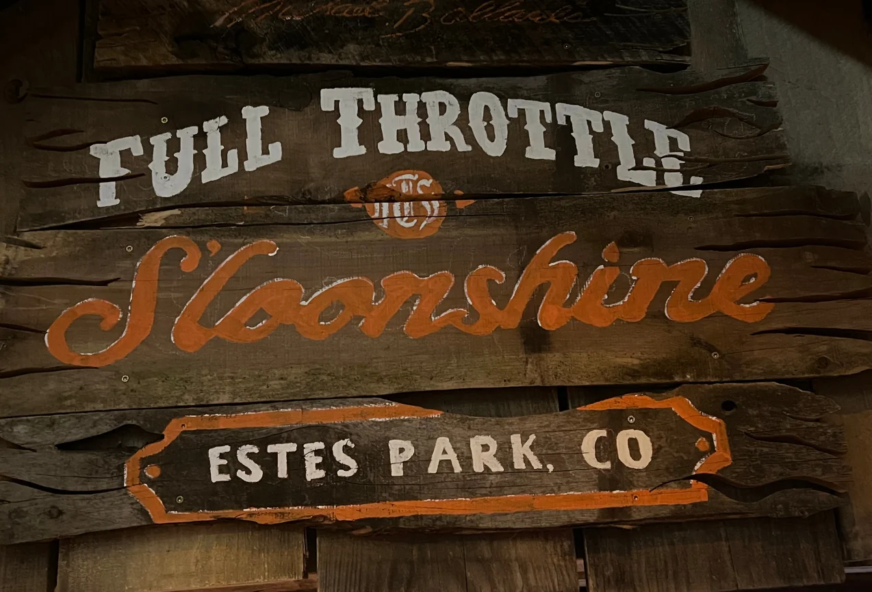 Rustic wooden Full Throttle Moonshine sign at Estes Park, highlighting a must-see stop on any list of what to visit in Estes Park.