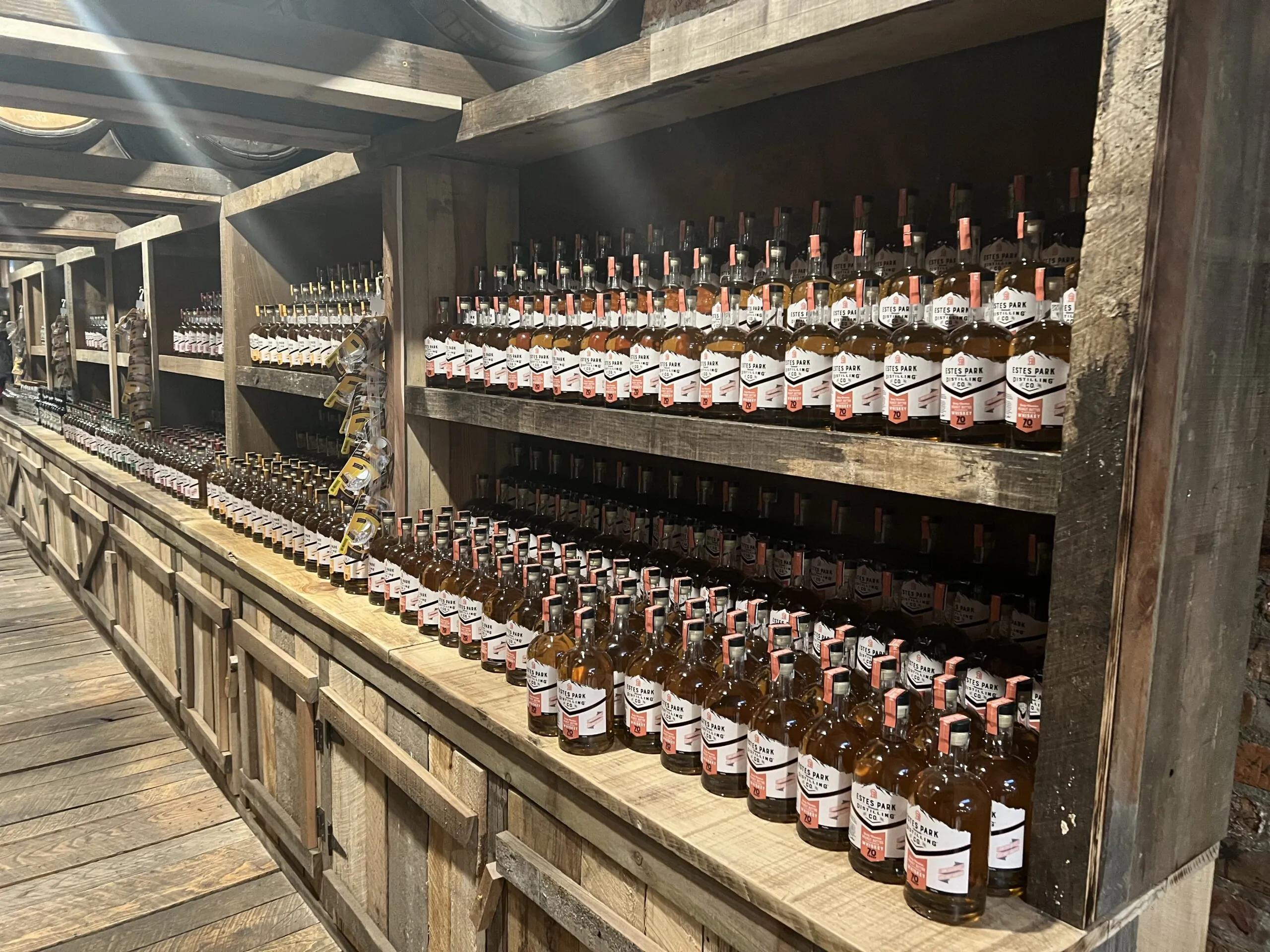 Full Throttle Distillery Drink bottles neatly arranged on wooden shelves at a rustic distillery