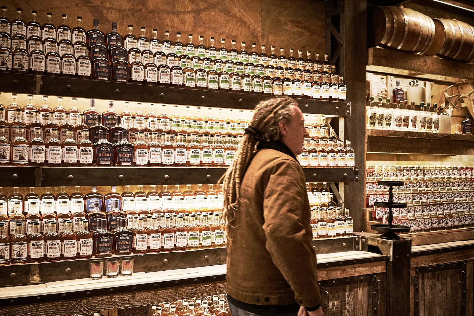 Michael Ballard inside Full Throttle Distillery in Deadwood, SD, surrounded by handcrafted moonshine and whiskey bottles