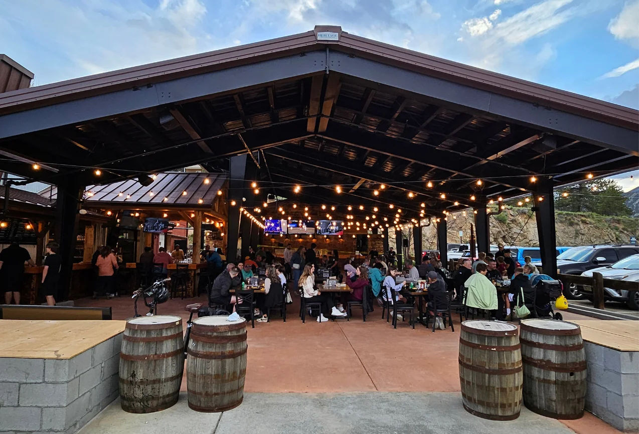 A busy outdoor patio with string lights and people dining at Full Throttle Distillery, a must-visit spot on any Estes Park Day Trip.