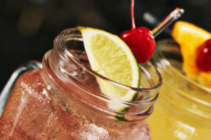 Mason jar cocktails with cherry and lime garnishes, perfect for unique holiday drinks ideas.